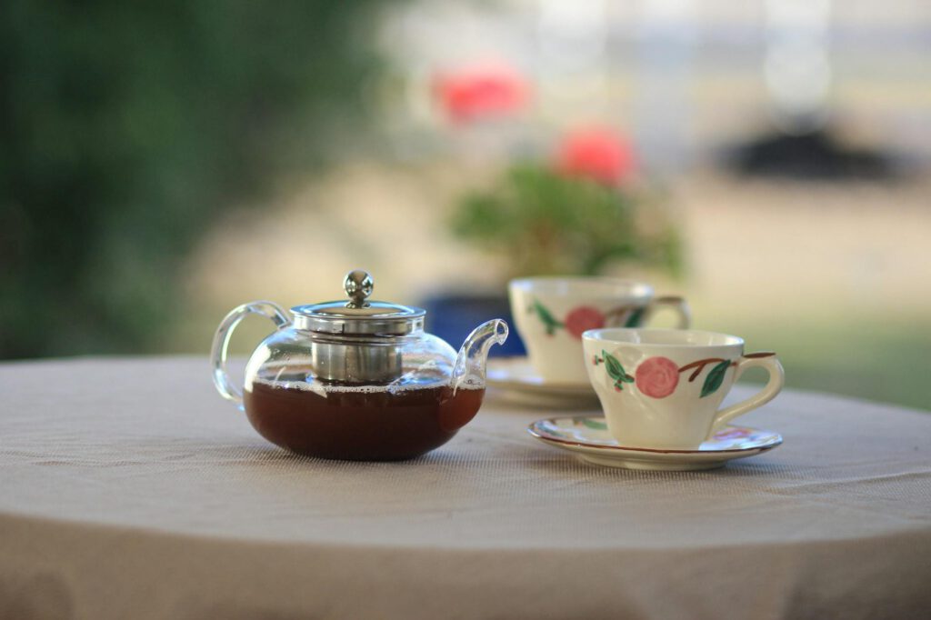 clear glass teapot near teacups on table selective focus photography